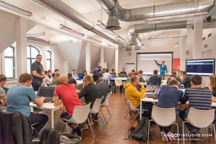 Workshop room at Meet Magento PL 2015, attendees with laptops at tables while a presenter points at the screen