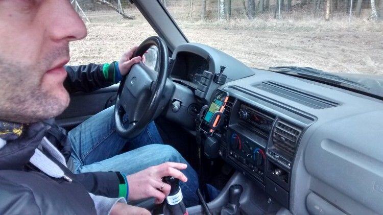 Driver's view inside a Land Rover with a smartphone running Trail Offroad mounted on the dashboard