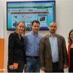 Four people posing at the Meet Magento stand at CeBIT 2013 in front of a screen