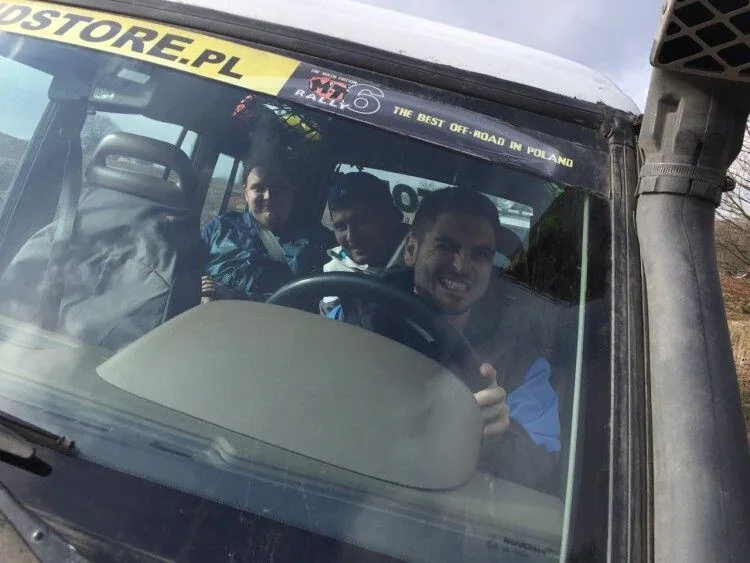 Smiling Snowdog team members inside a 4x4 on the off-road route, seen through the windscreen