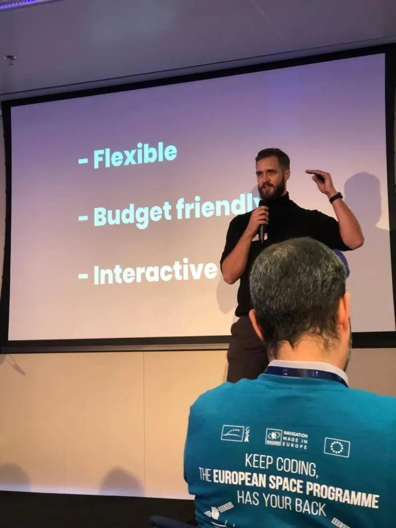 Speaker pitching on stage in front of a slide reading Flexible, Budget friendly, Interactive