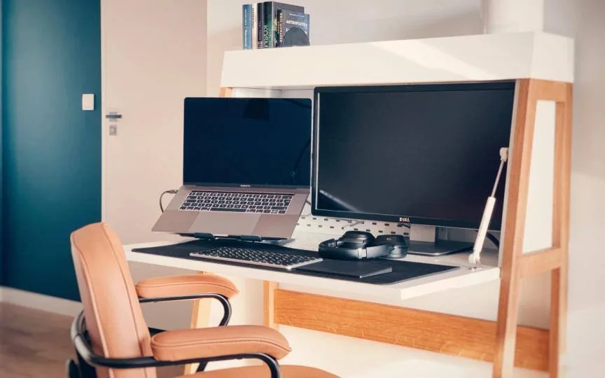 Artur's compact home workspace with a MacBook on a stand, a Dell monitor, headphones and a leather office chair