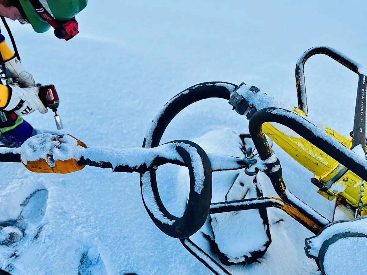 Worker fastening the bolts of an AcuSense node on a snowy trailing cable