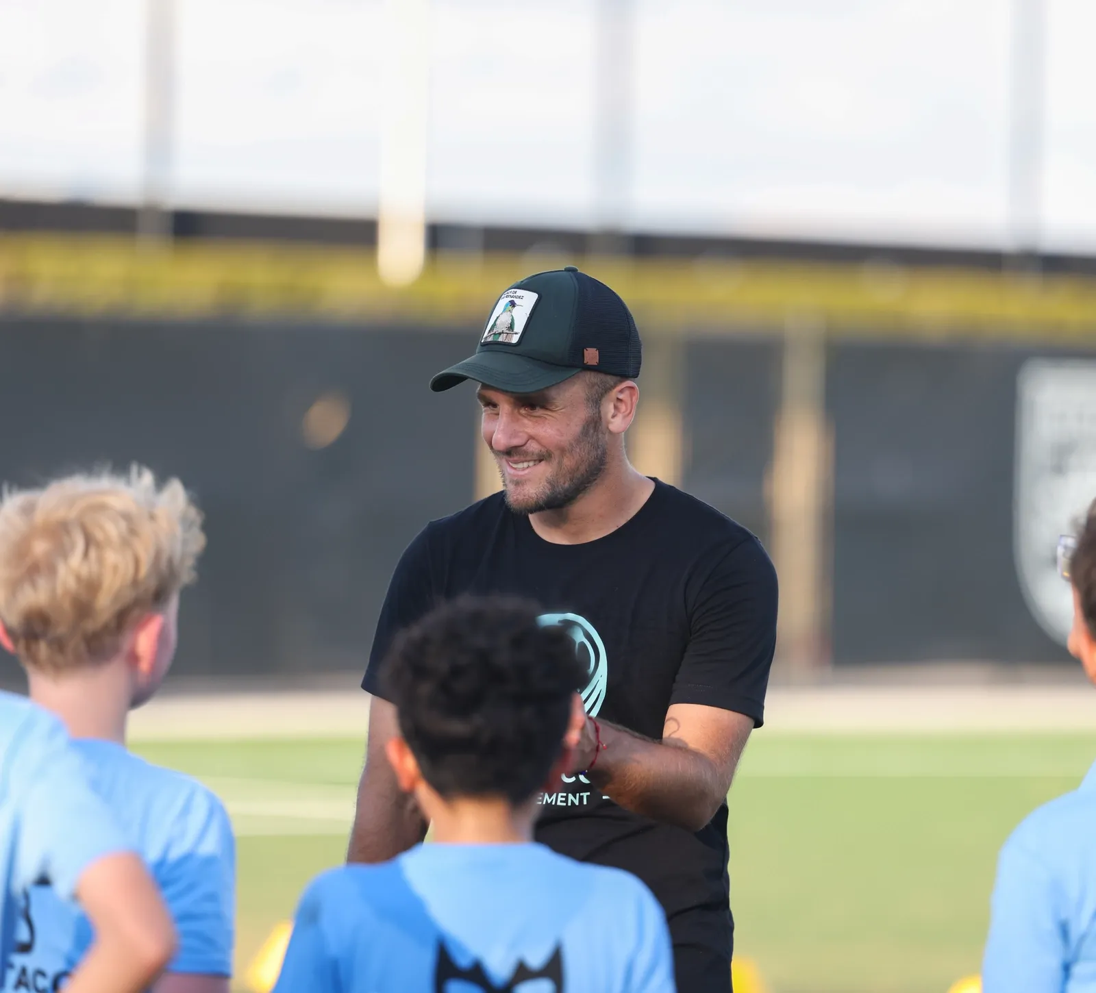 Pro player coach talking with young players at a TURF ATX youth soccer camp