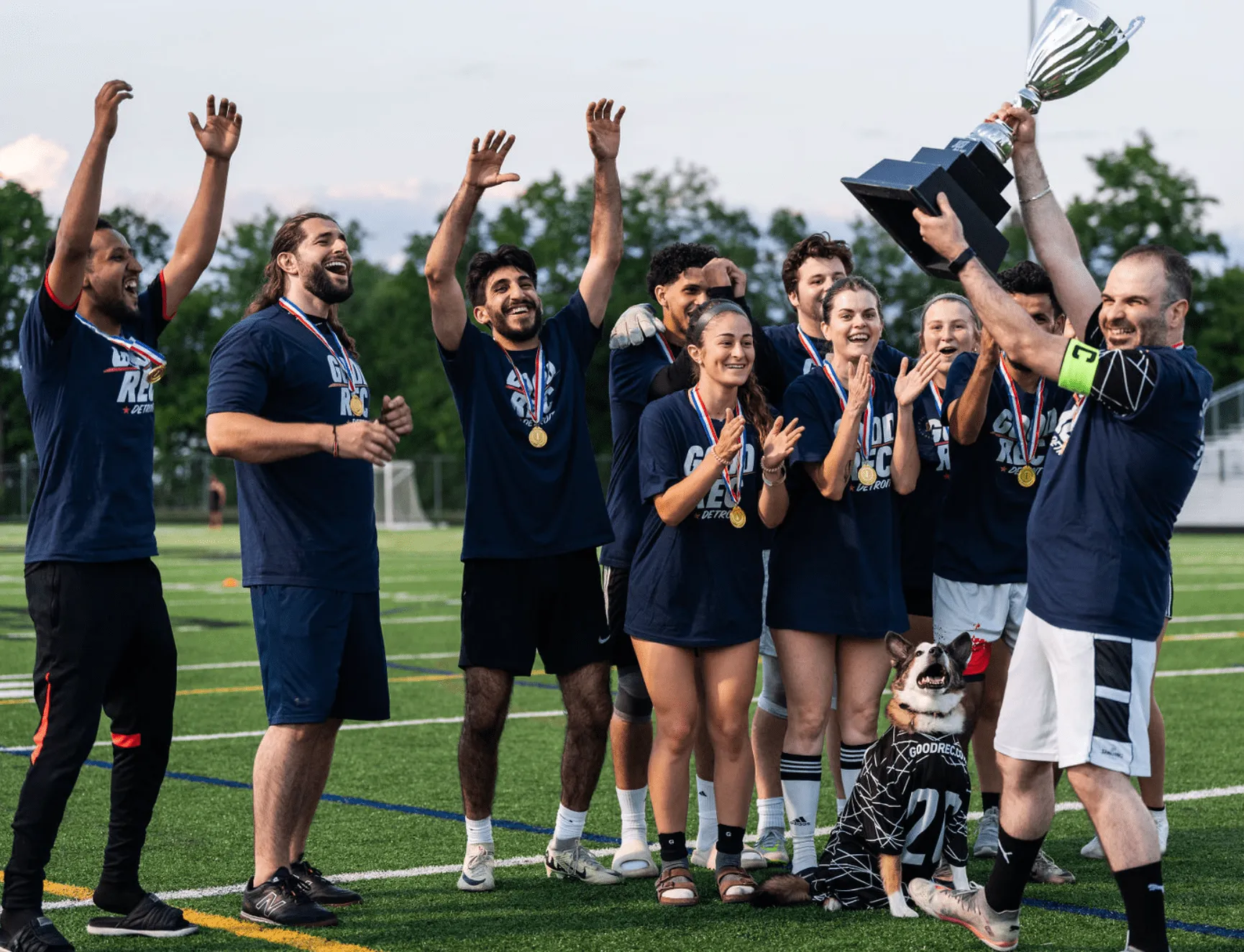 Adult rec league soccer team celebrating with medals and a championship trophy