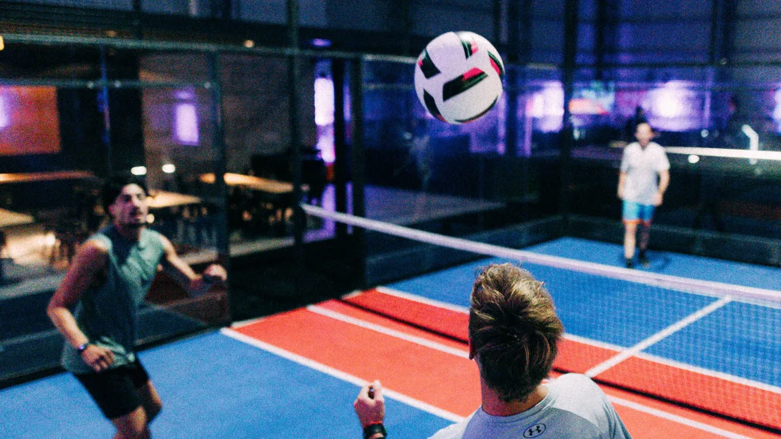 Players rallying a ball over the net on the soccer tennis court at TURF ATX