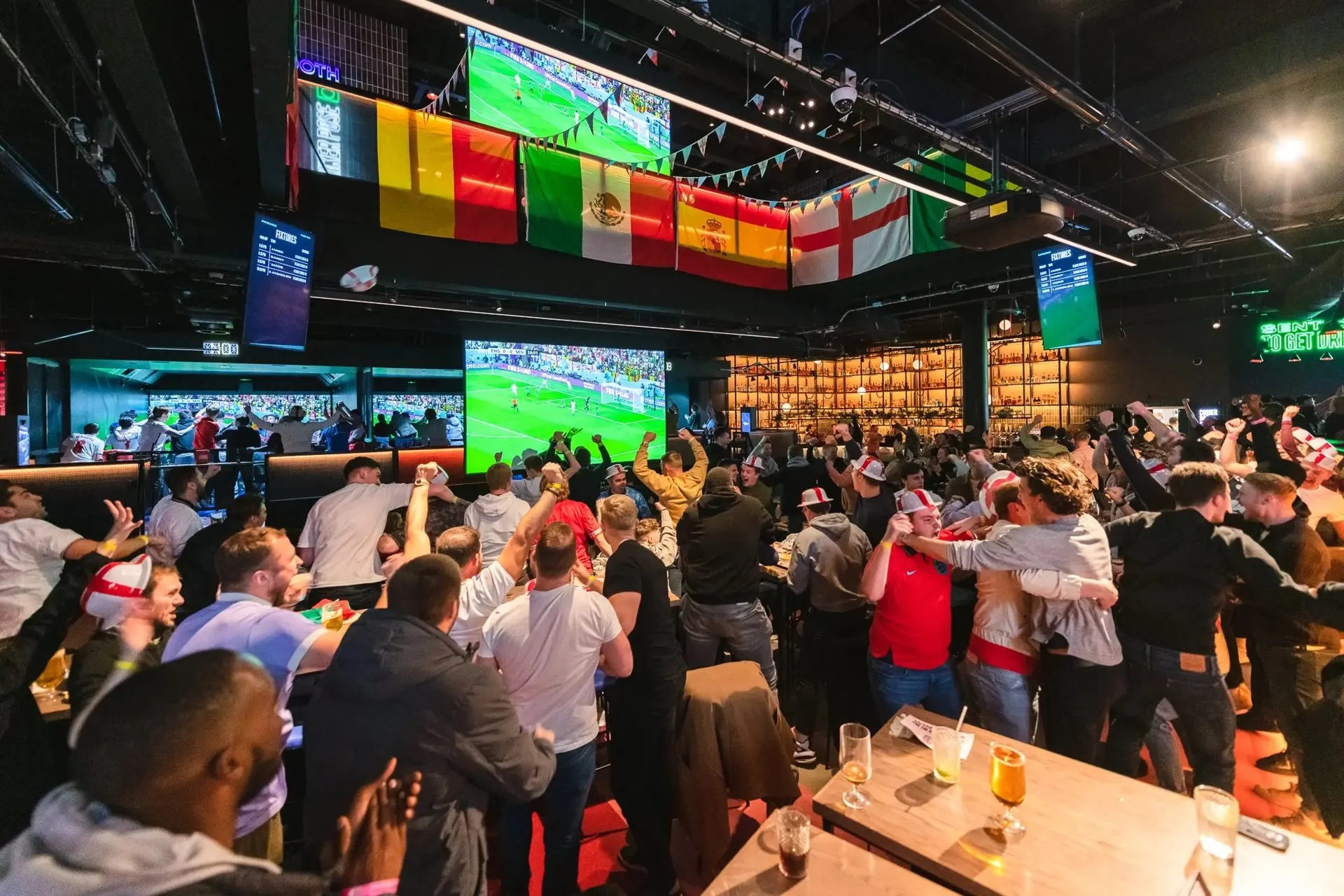 Soccer fans cheering a match on big screens in the TURF ATX Watchzone