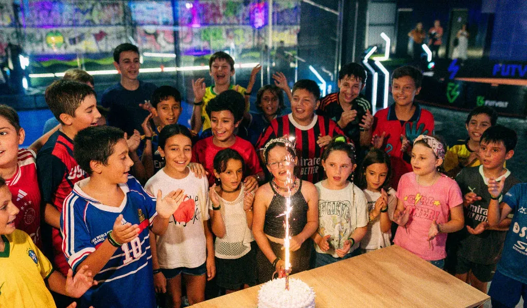 Kids in soccer jerseys laughing over burgers and fries at a birthday party at TURF