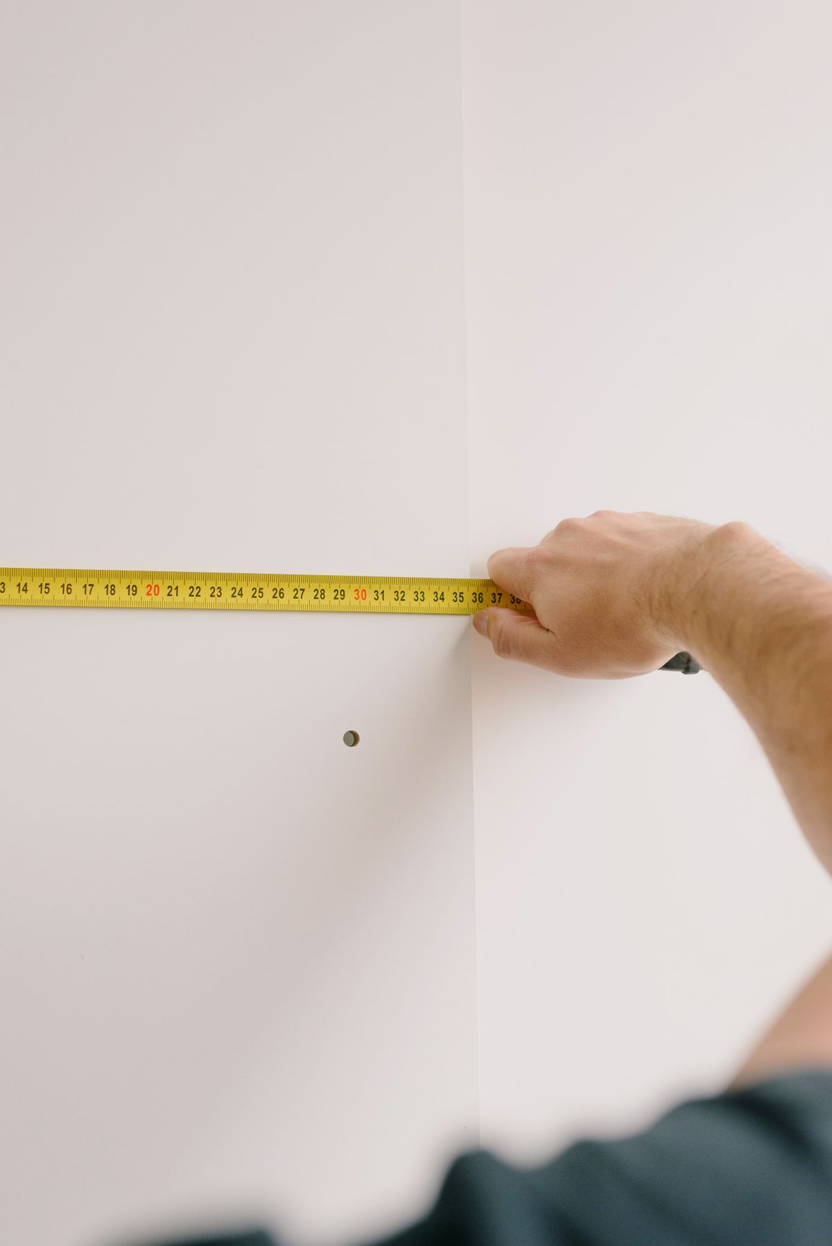A person measuring a wall before home preparation work