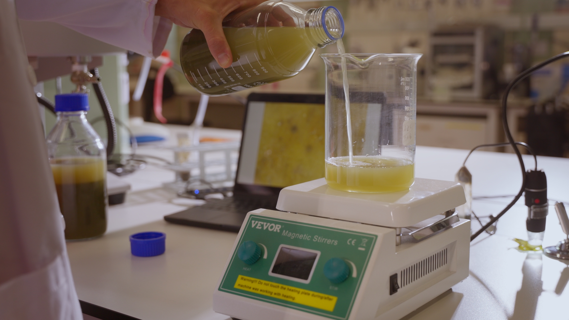 Liquid being poured into a beaker on laboratory equipment.