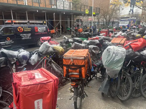 A concentration of delivery bicycles, mopeds, and equipment on a New York City street