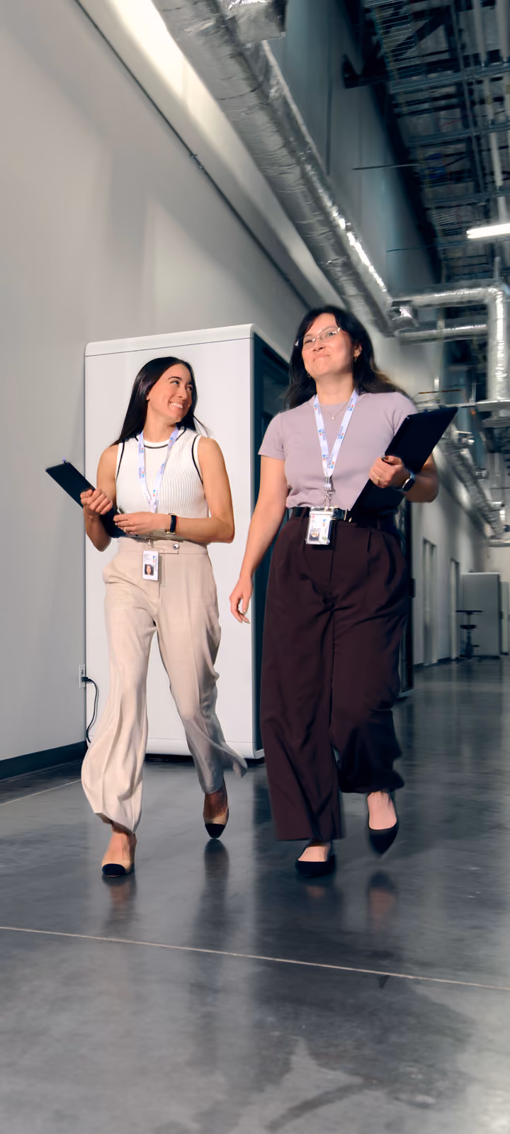 Two women walking down office hallway