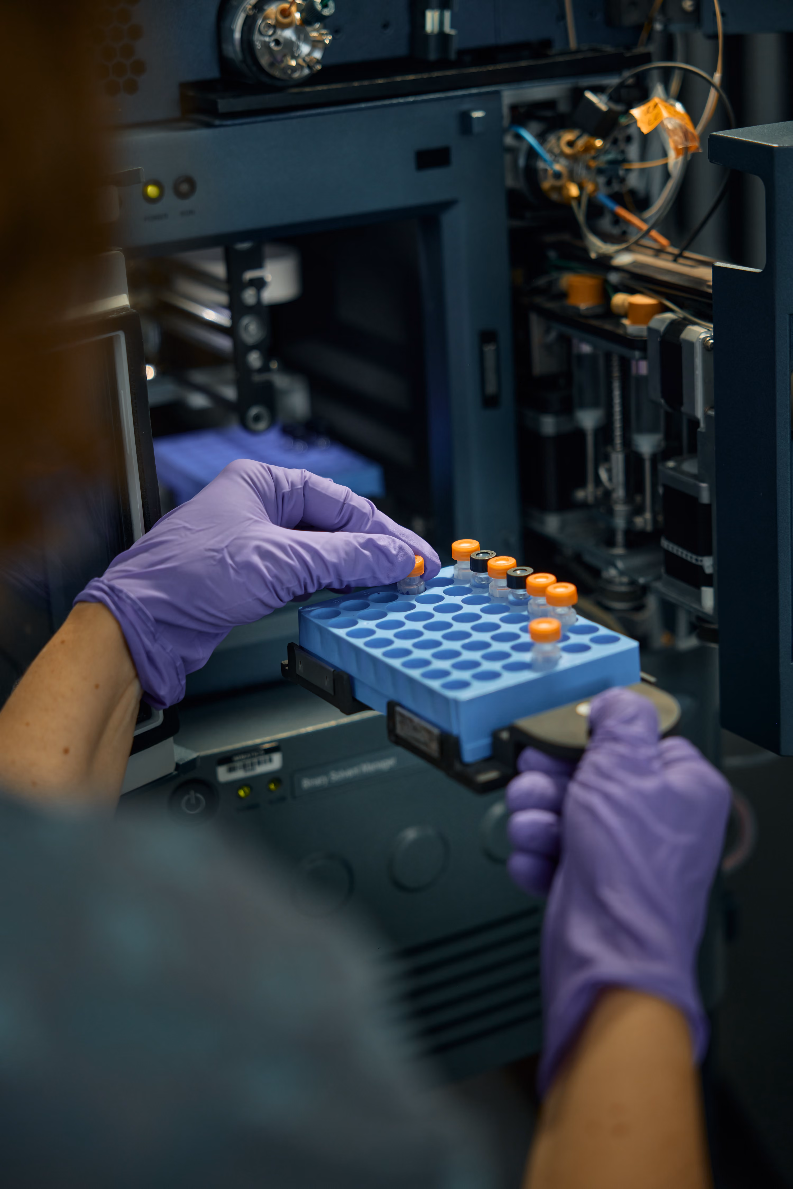 Gloved hands holding test tube samples in a lab