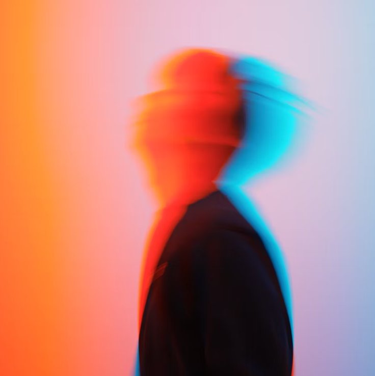 Blurred silhouette of a figure against a coloured background