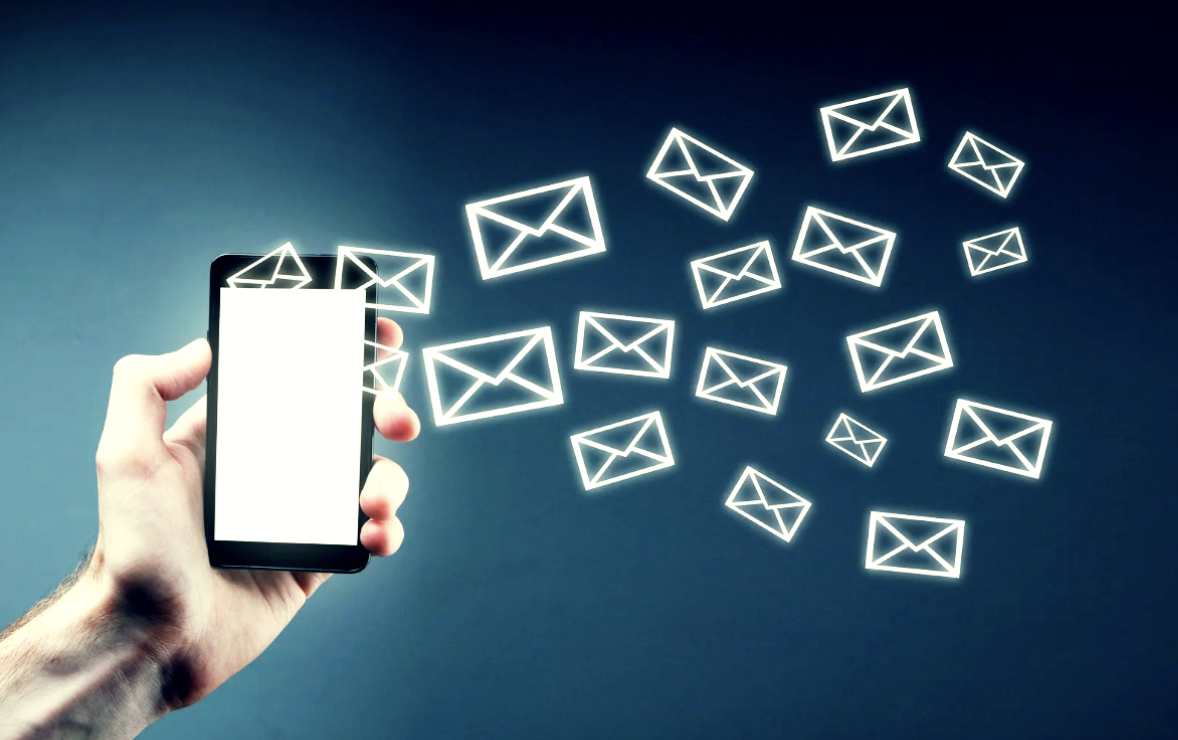 Hand holding smartphone with glowing email icons floating outward, representing email and digital communication.