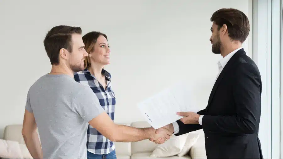 A couple shaking hands with a business representative to establish rent reporting services