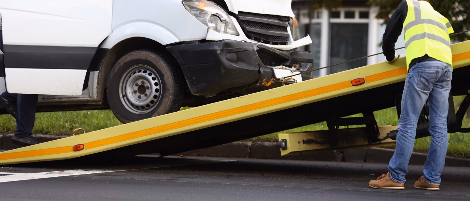 Damaged van being loaded onto a tilt-tray tow truck