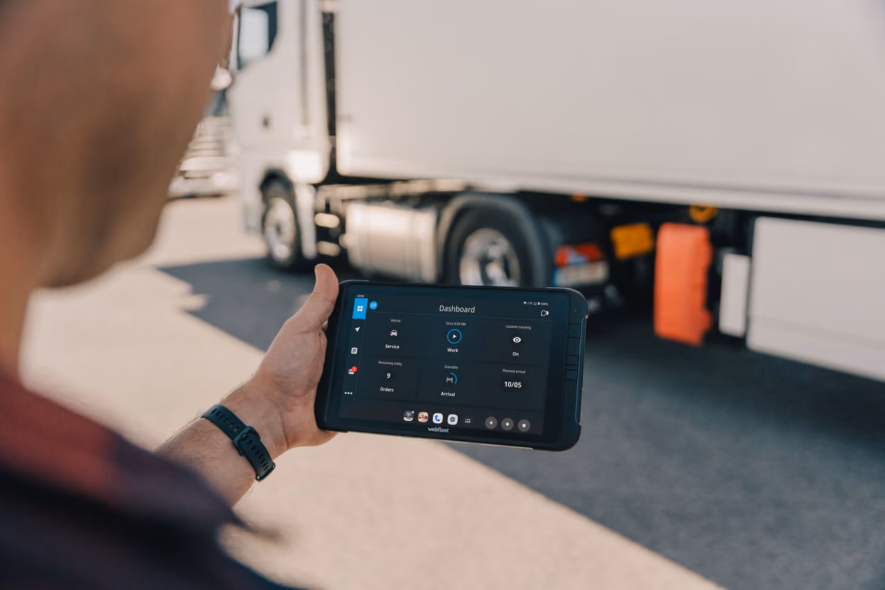 Driver completing a pre-start check on a tablet beside a truck