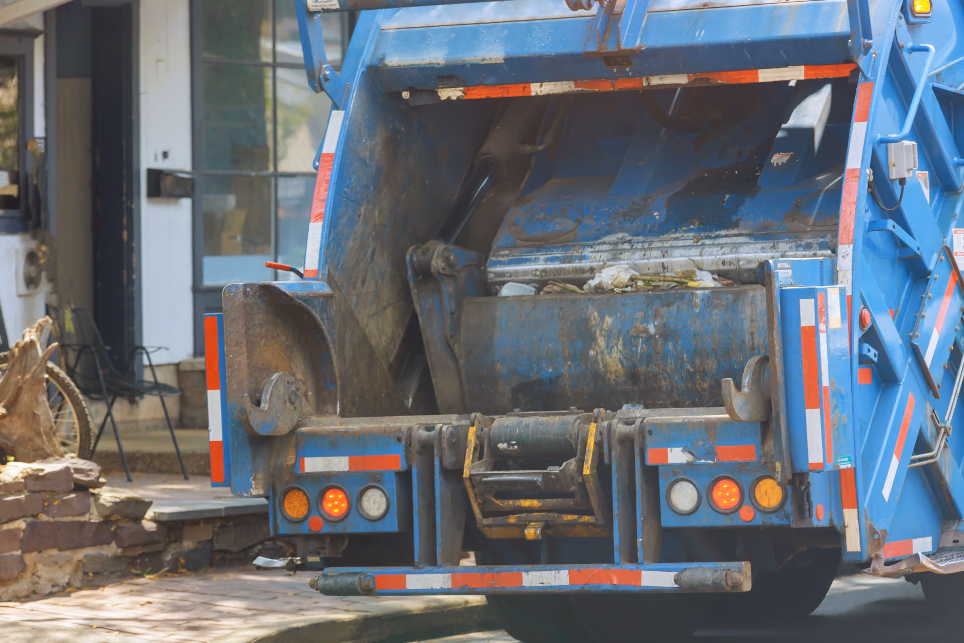 Rear hopper of a blue refuse compactor truck on a collection round
