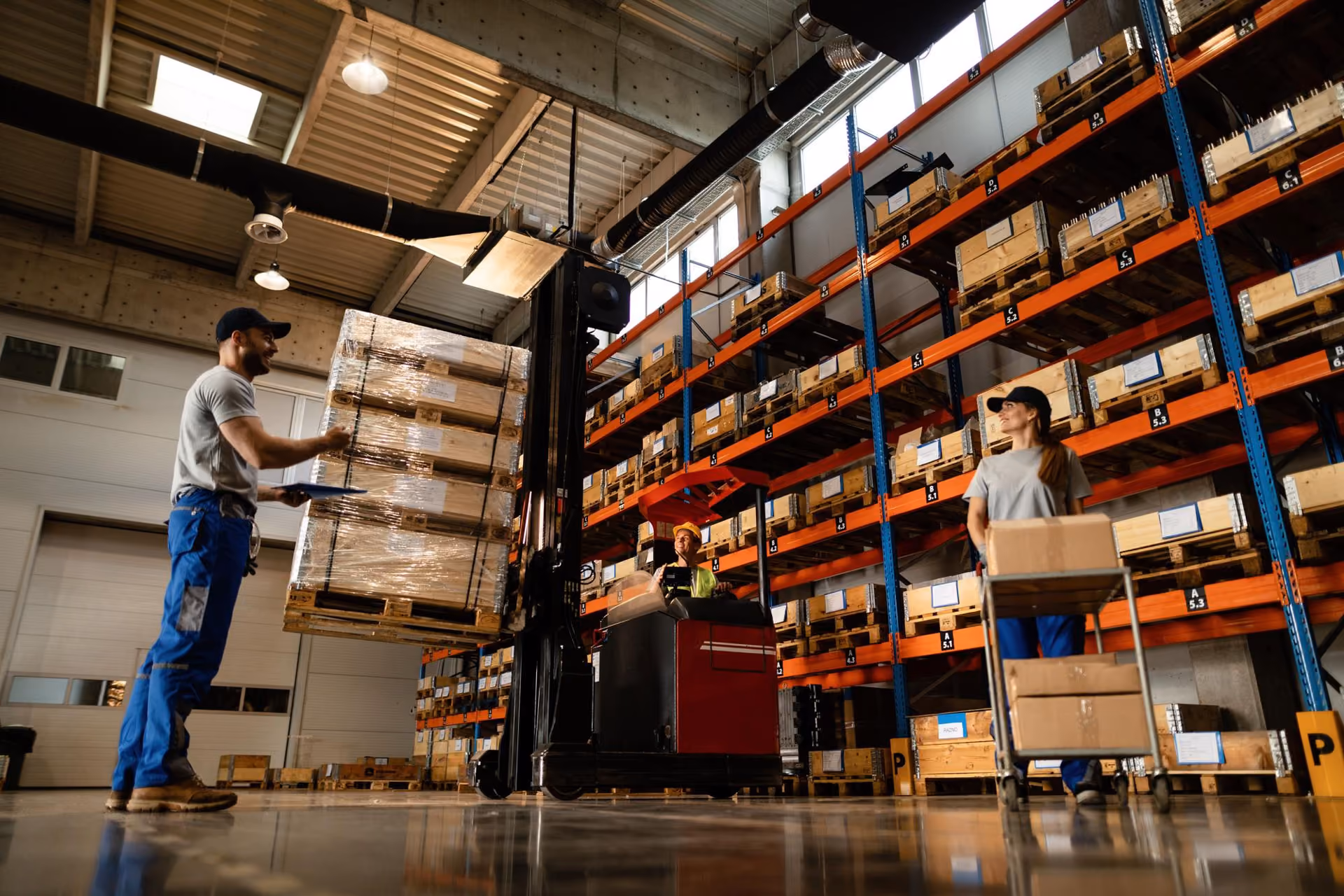 Warehouse team moving palletised freight with a reach truck beside racking