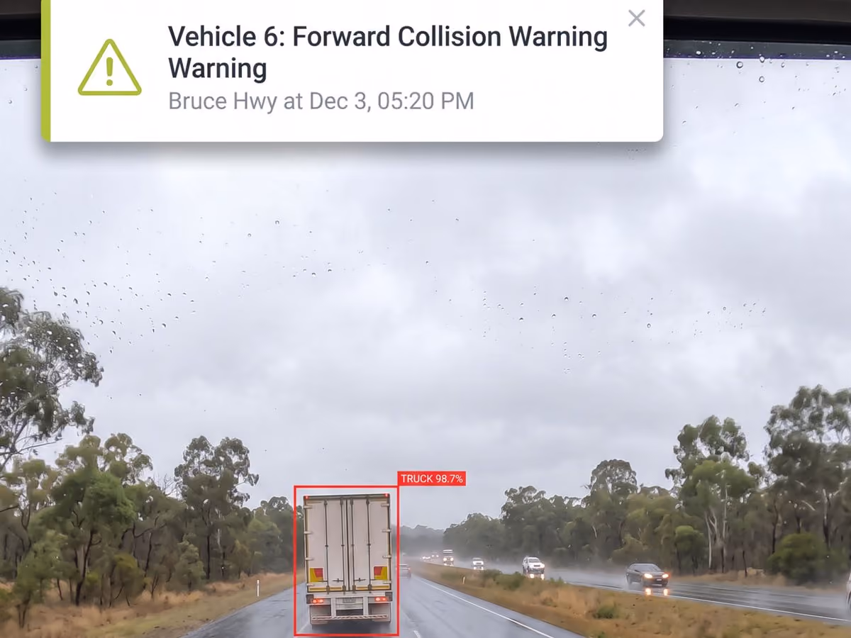 In-cab view in heavy rain with a forward collision warning alert for a truck ahead on the Bruce Highway