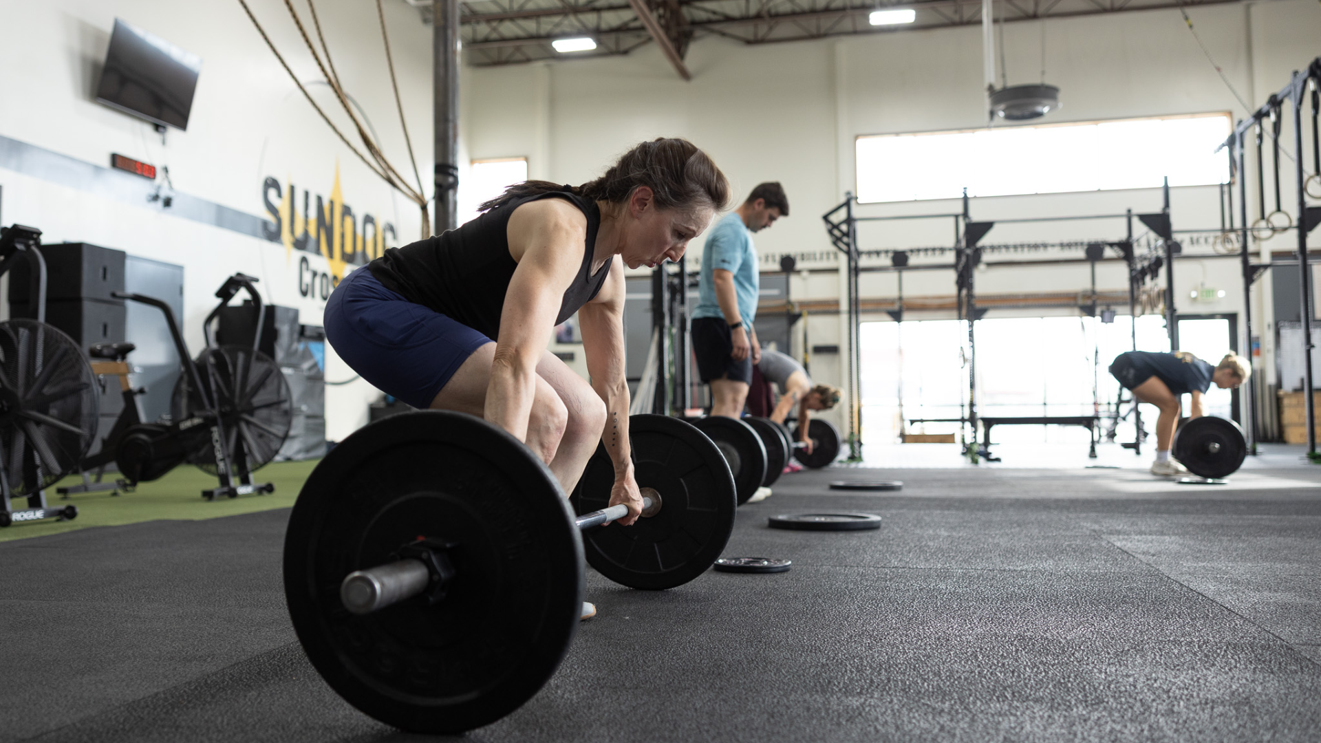 Woman performing a barbell deadlift during a group CrossFit workout at Sundog CrossFit in Fairbanks, Alaska.