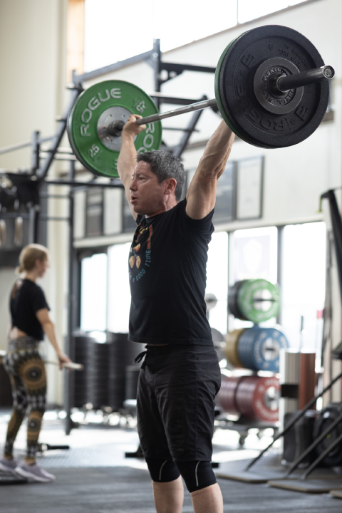 Man lifting a barbell overhead during a CrossFit Light class at Sundog CrossFit in Fairbanks, Alaska.
