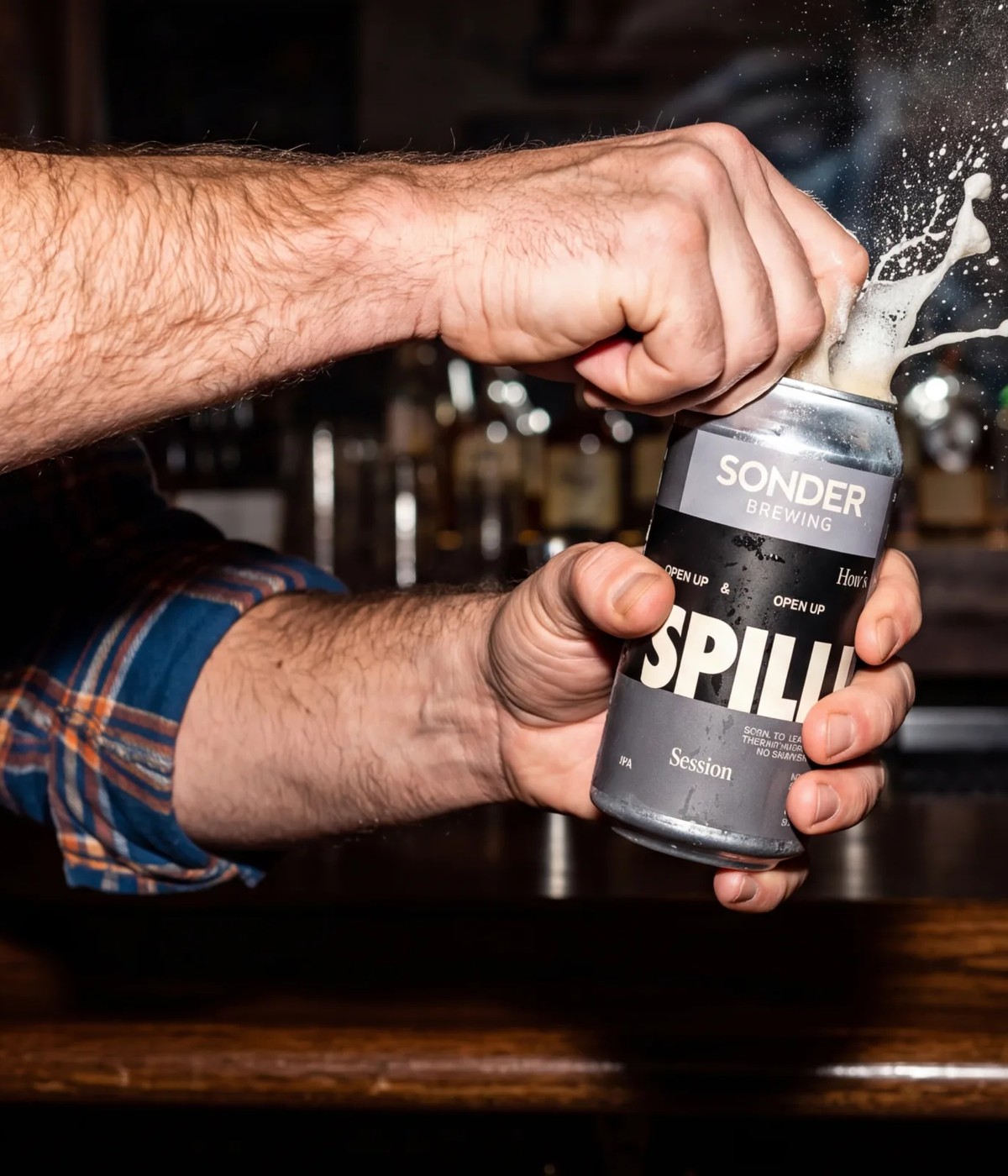 Hands cracking open a can of SPILL! IPA at a bar