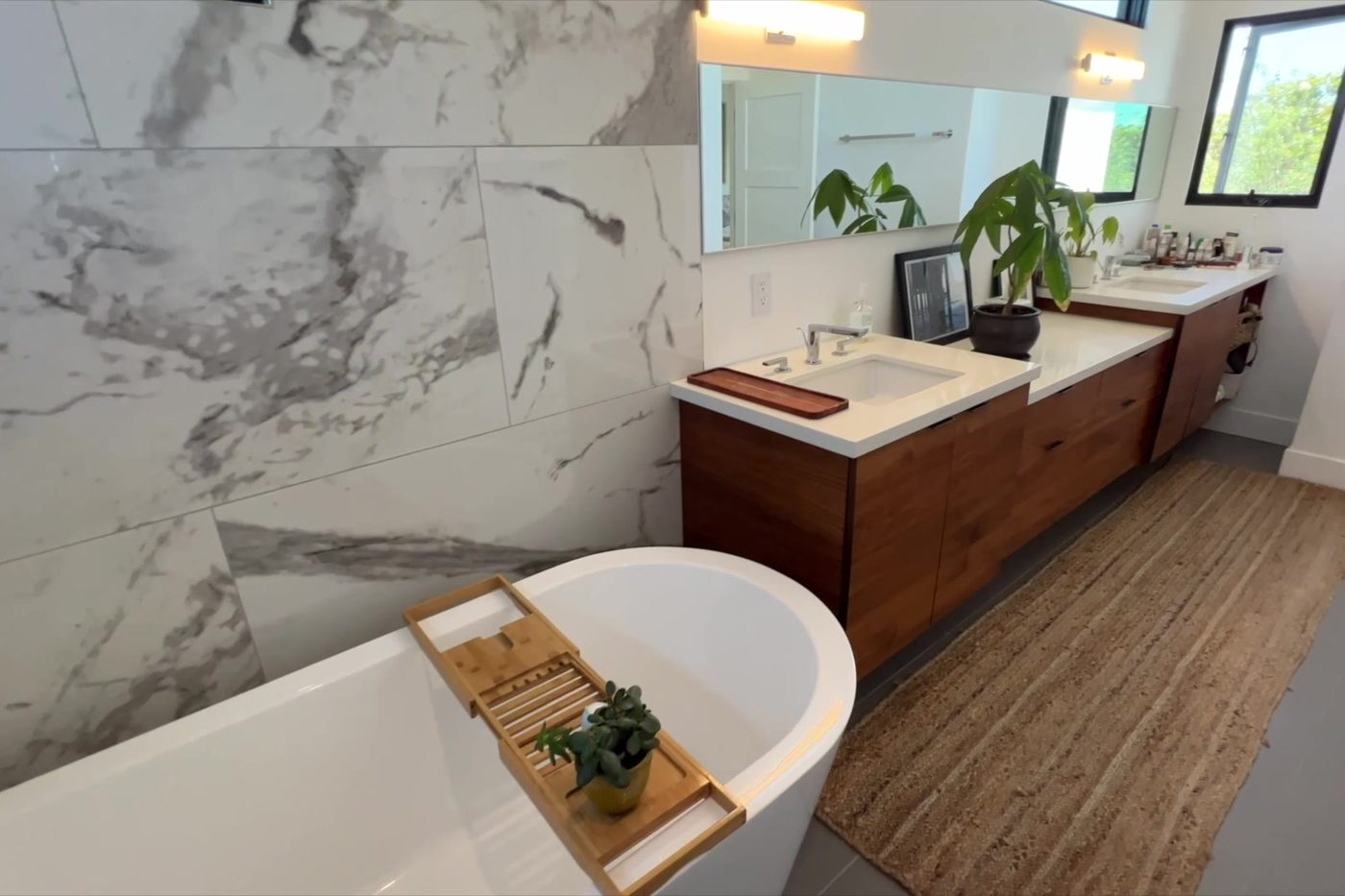 The Modern Monica bathroom: freestanding tub, marble-look tile and a double wood vanity.