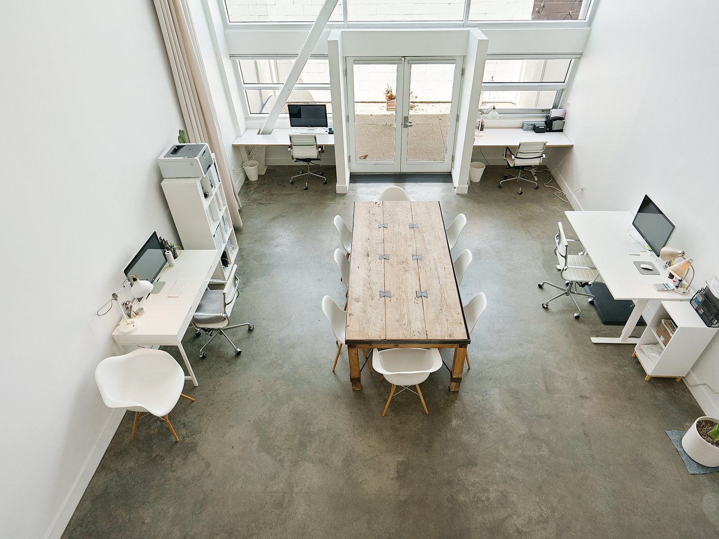 The same Venice studio loft from above after prep: clear desks, bare walls and light from the tall windows
