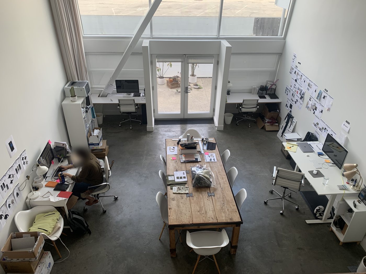 Venice studio loft from above before prep: desks covered in work, papers pinned to the walls