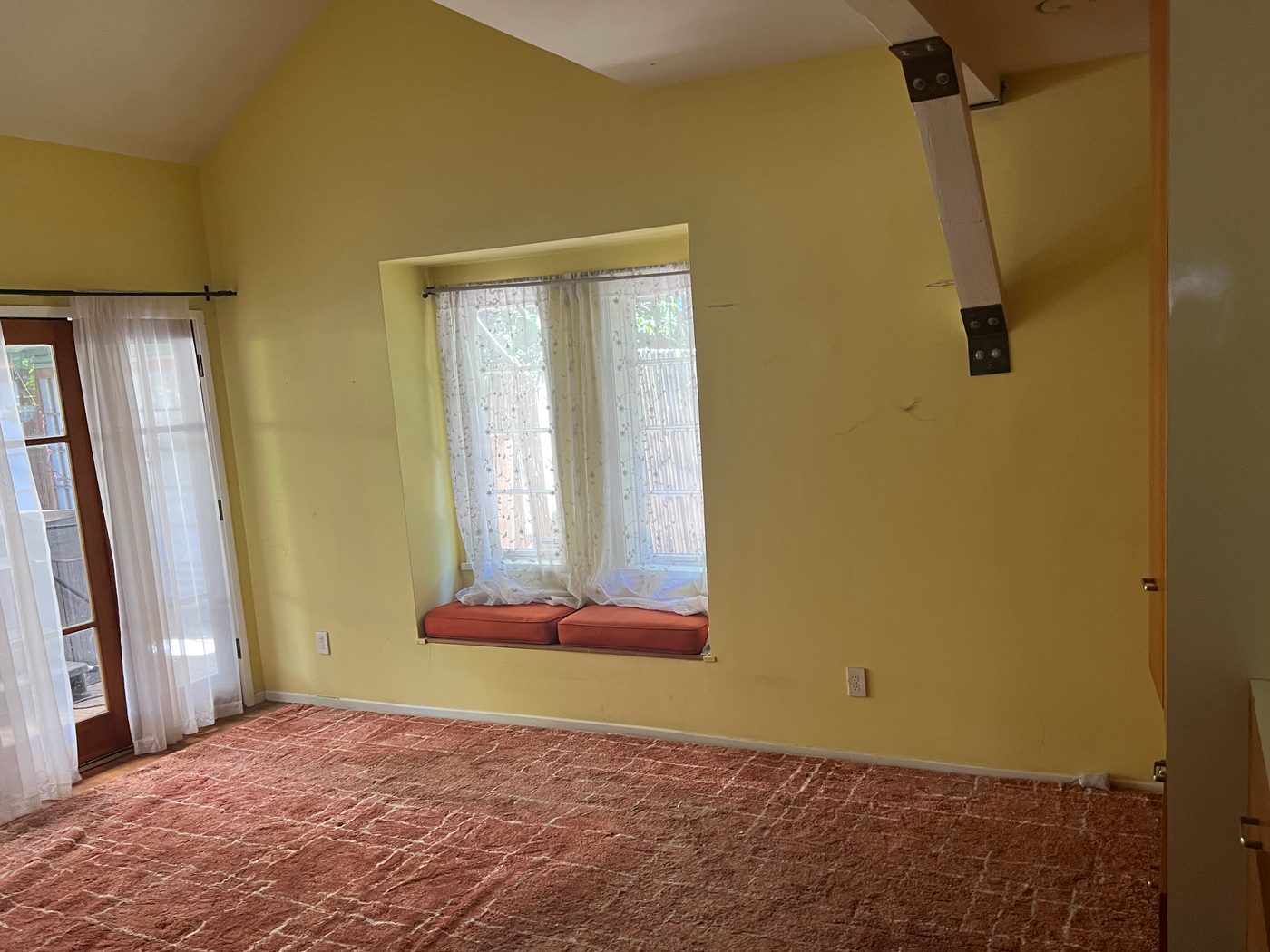 Los Feliz bedroom before: yellow walls and worn red carpet
