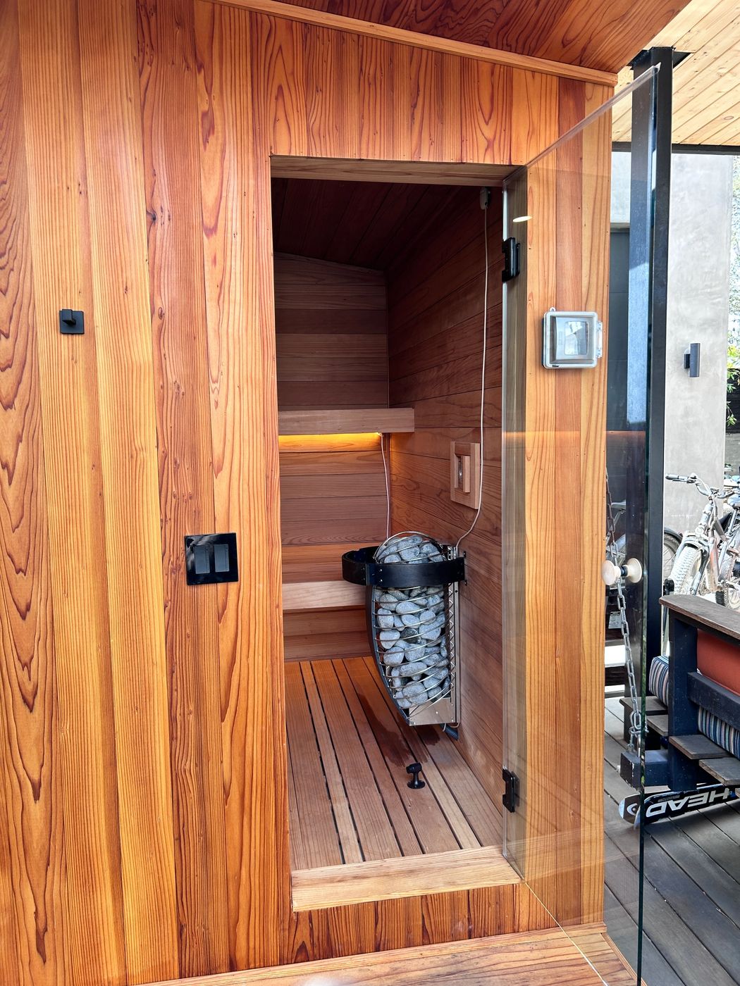 Looking through the open glass door at the heater and redwood benches