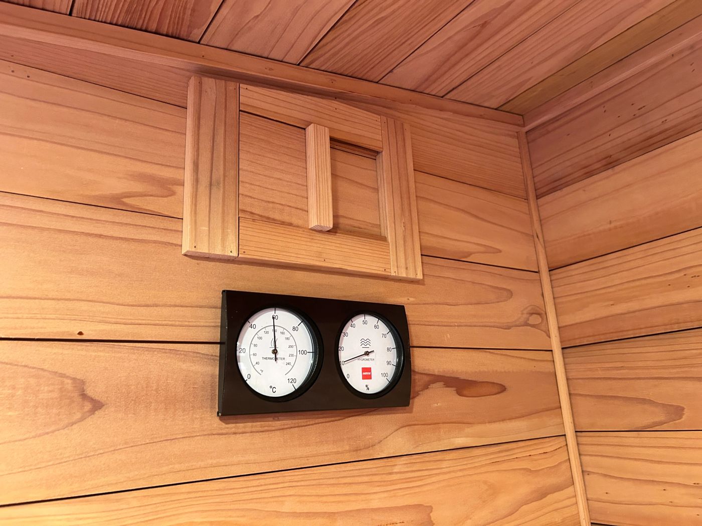 Thermometer and hygrometer below a wooden vent cover
