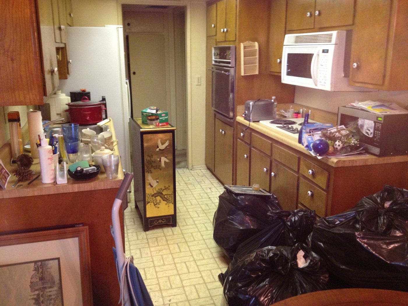 Brentwood condo kitchen before: crowded counters and trash bags on the floor