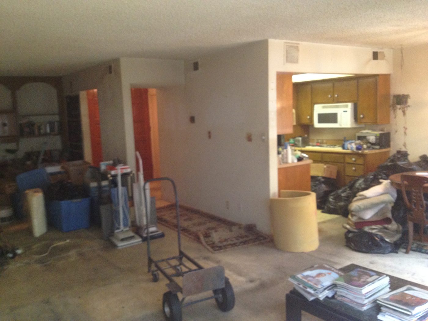 Brentwood condo living room mid-cleanout: boxes, a hand truck and stacks of magazines