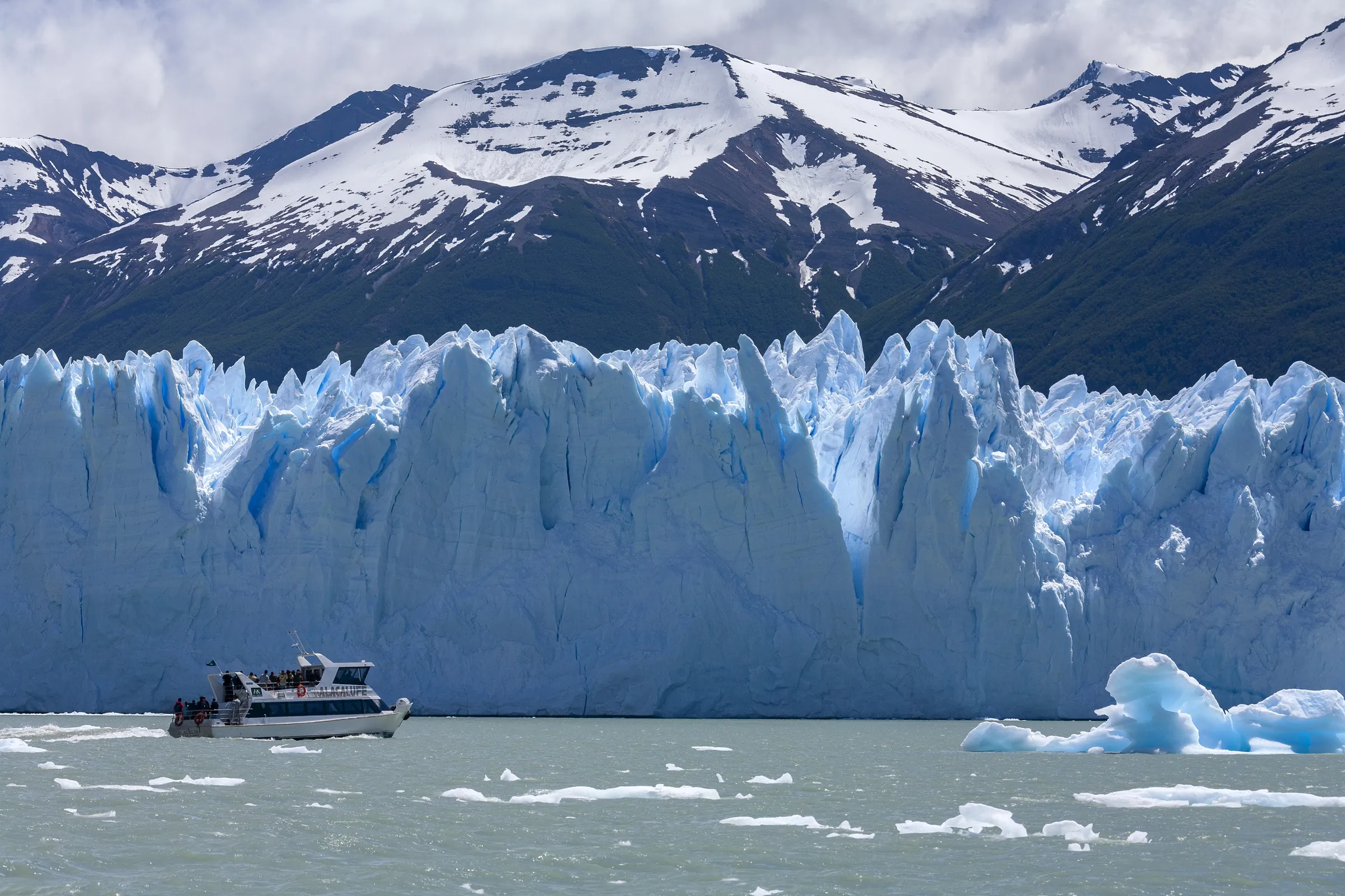Boat beside the towering face of a glacier