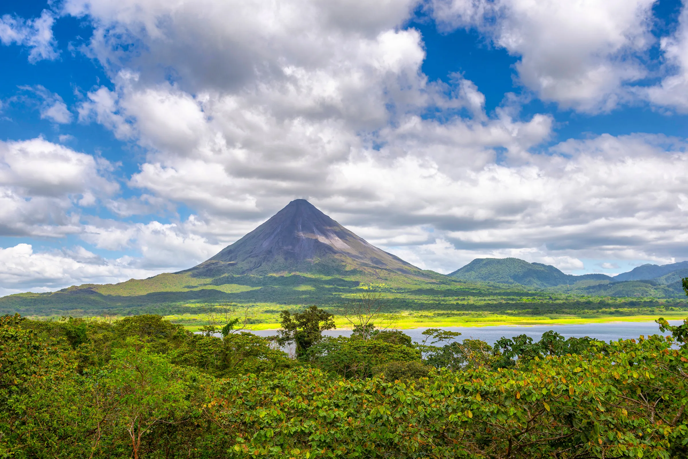 Arenal Volcano above green forest and lake