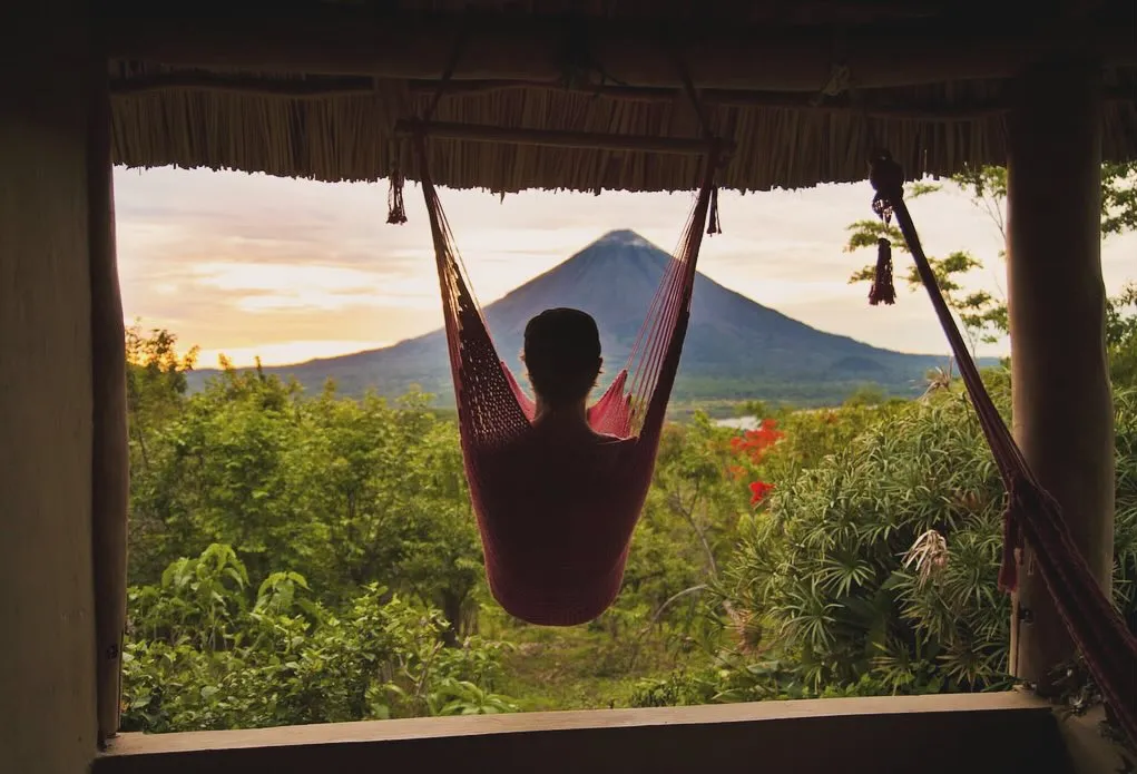Man relaxing in a hammock overlooking a volcano on Ometepe, Nicaragua.