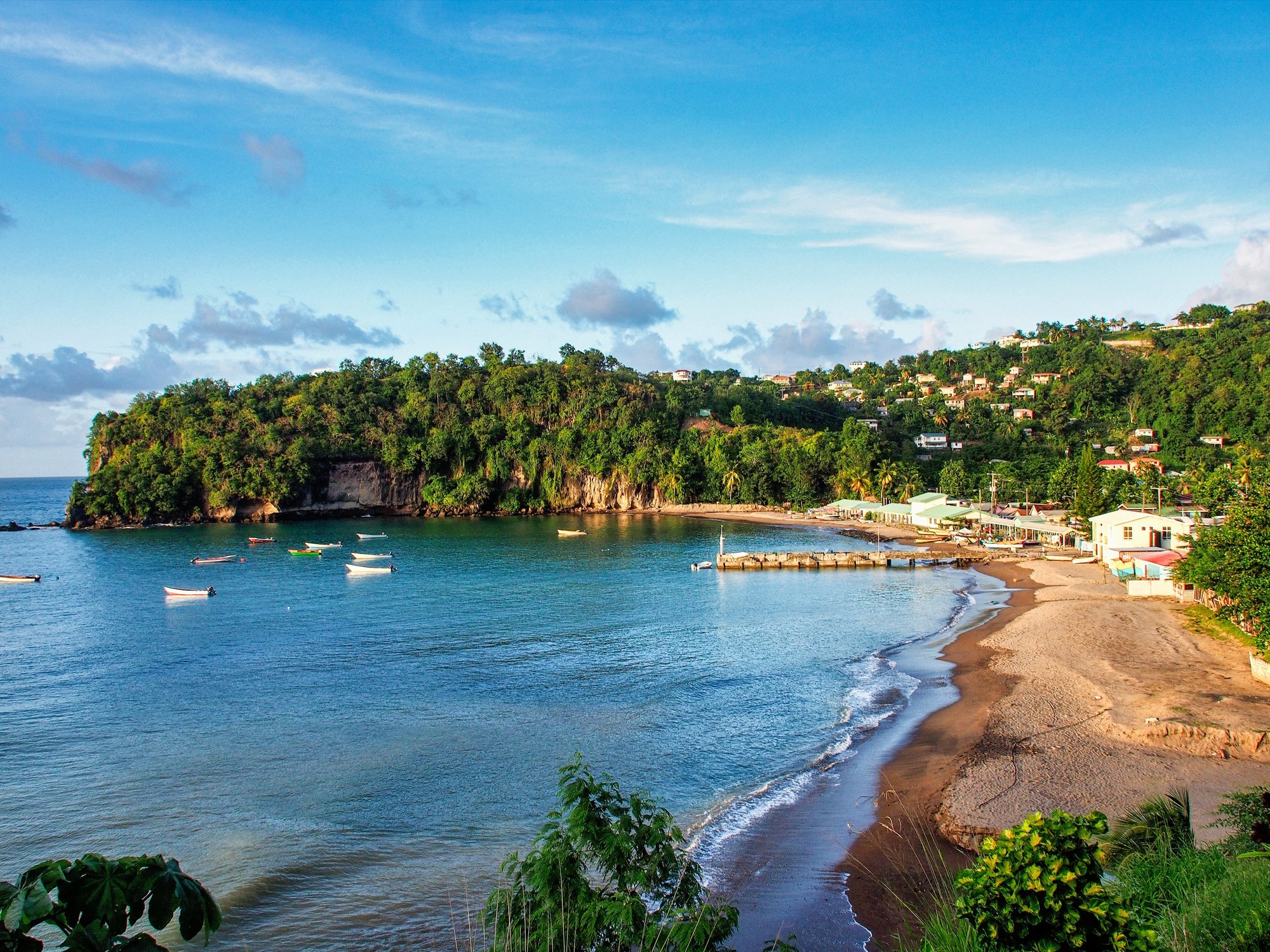 Boats in a sheltered bay below a hillside village in Grenada.
