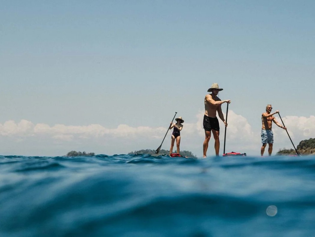 A group of guests stand-up paddleboarding on calm Pacific waters near Islas Secas.
