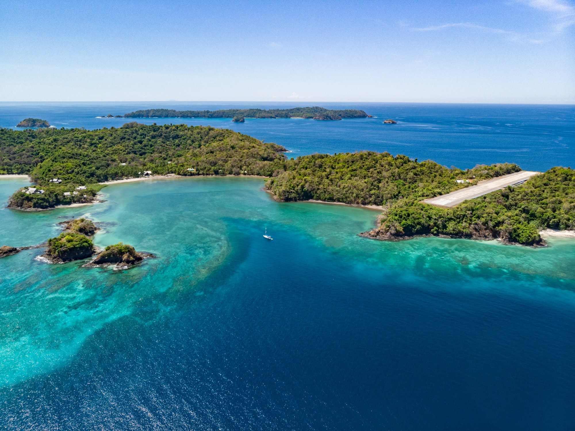 Aerial view of the forested Islas Secas archipelago and its private airstrip surrounded by turquoise Pacific waters.