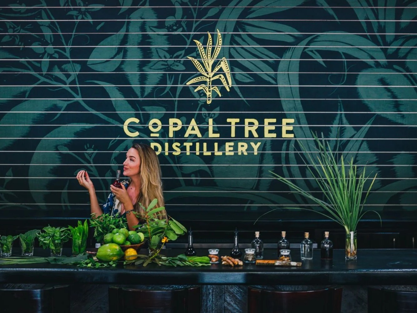 A guest samples rum surrounded by fresh botanicals at Copal Tree Distillery.