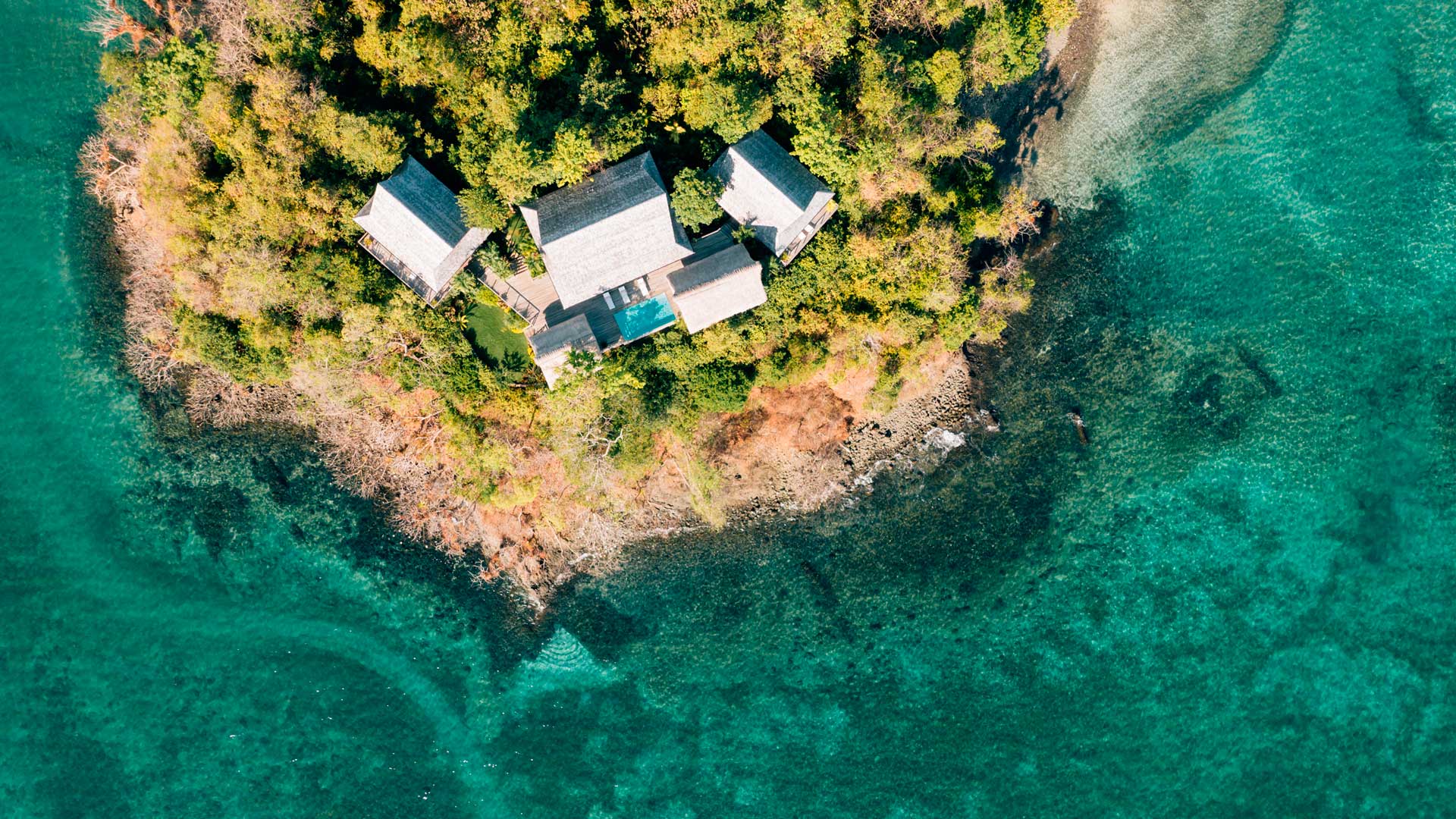 Waterfront bungalows on a private island surrounded by clear water.