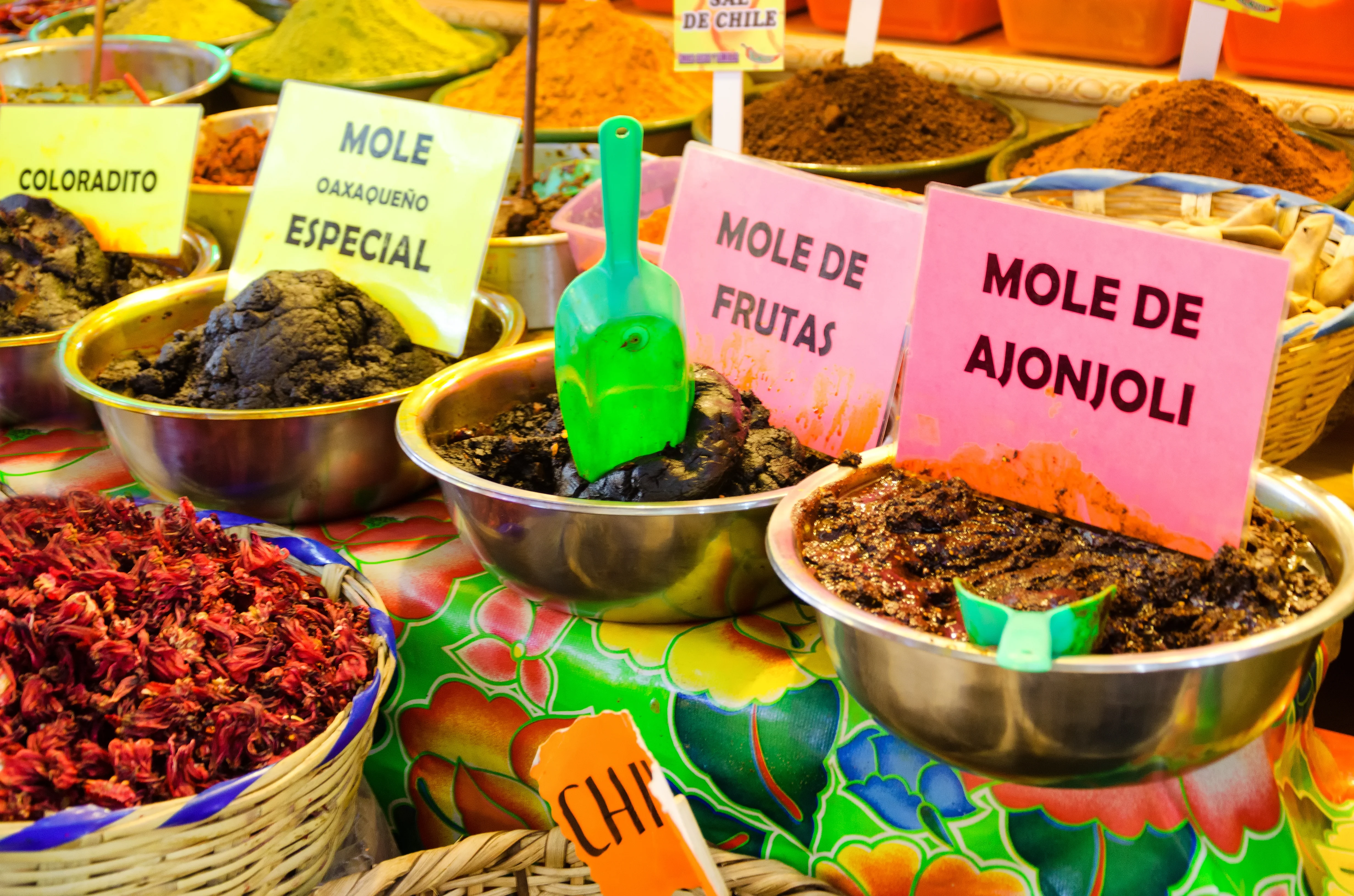 Metal bowls with various types of mole sauces and chili powders on a colorful tablecloth. Oaxaca, Mexico.