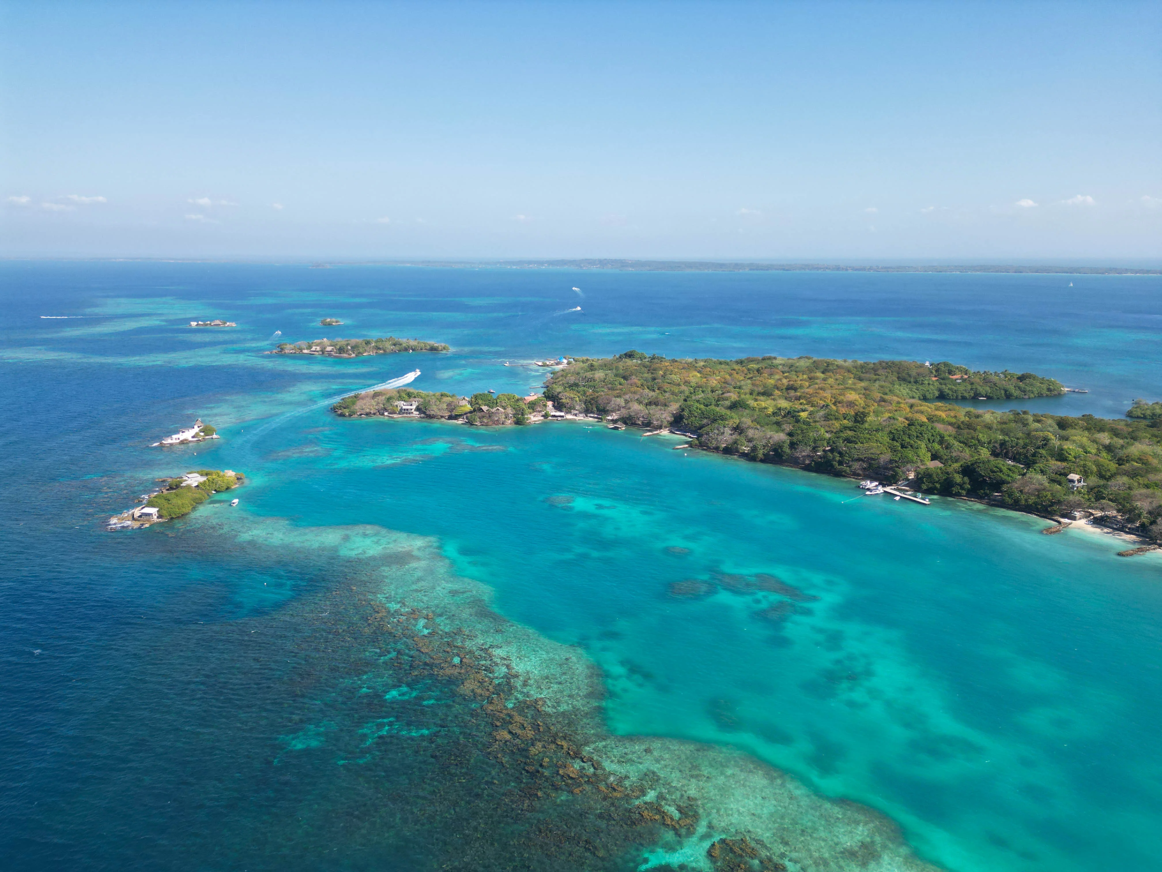 Aerial view of lush green islands surrounded by turquoise and deep blue ocean waters. Islas del Rosario, Colombia.
