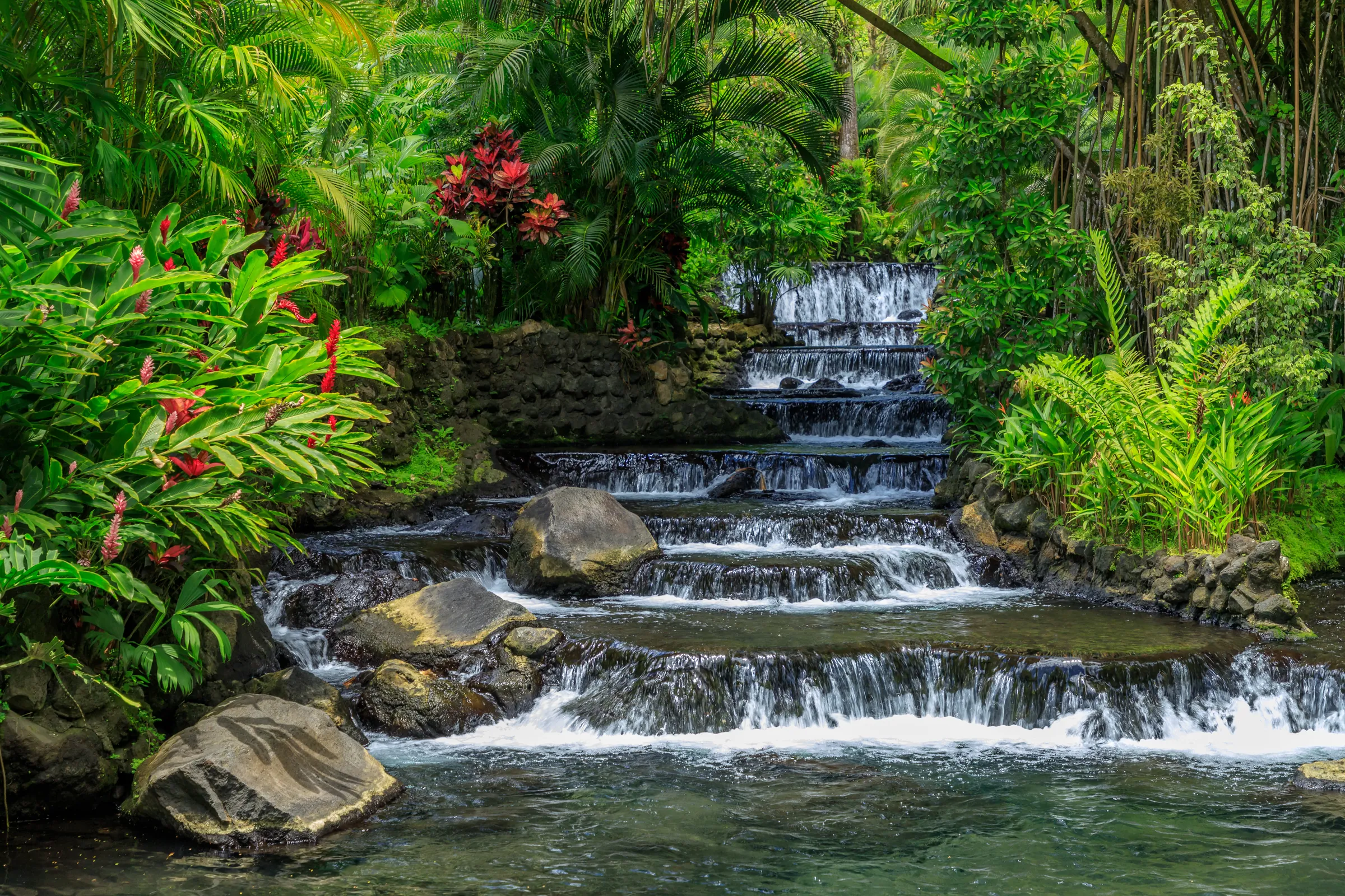 Tiered hot spring cascades surrounded by tropical vegetation