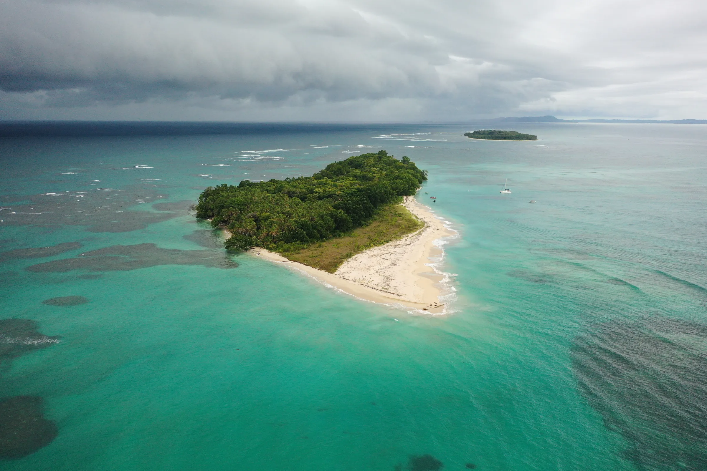 Aerial view of a forested island with a pale sandy spit