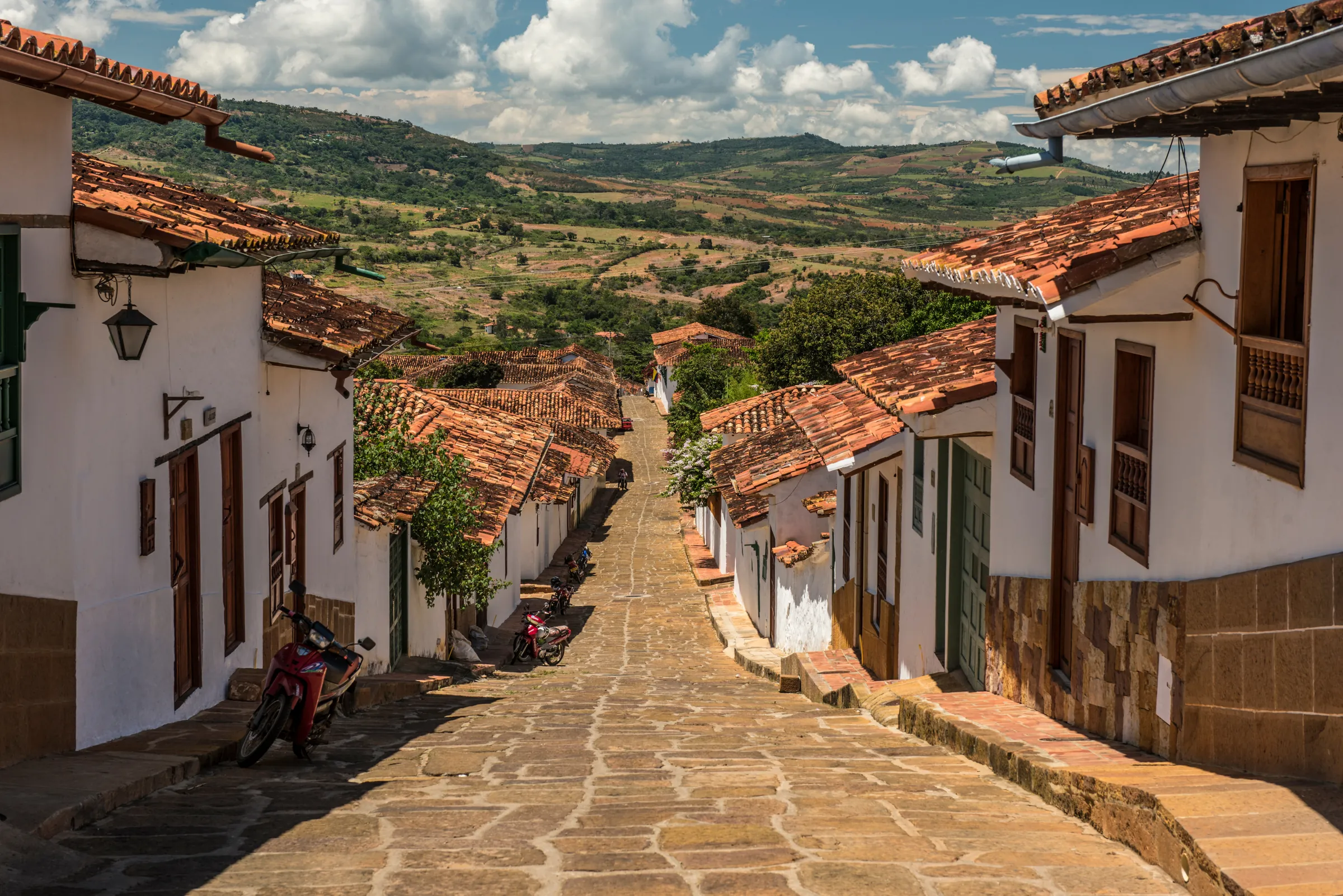 Cobblestone street descending between whitewashed houses in Barichara