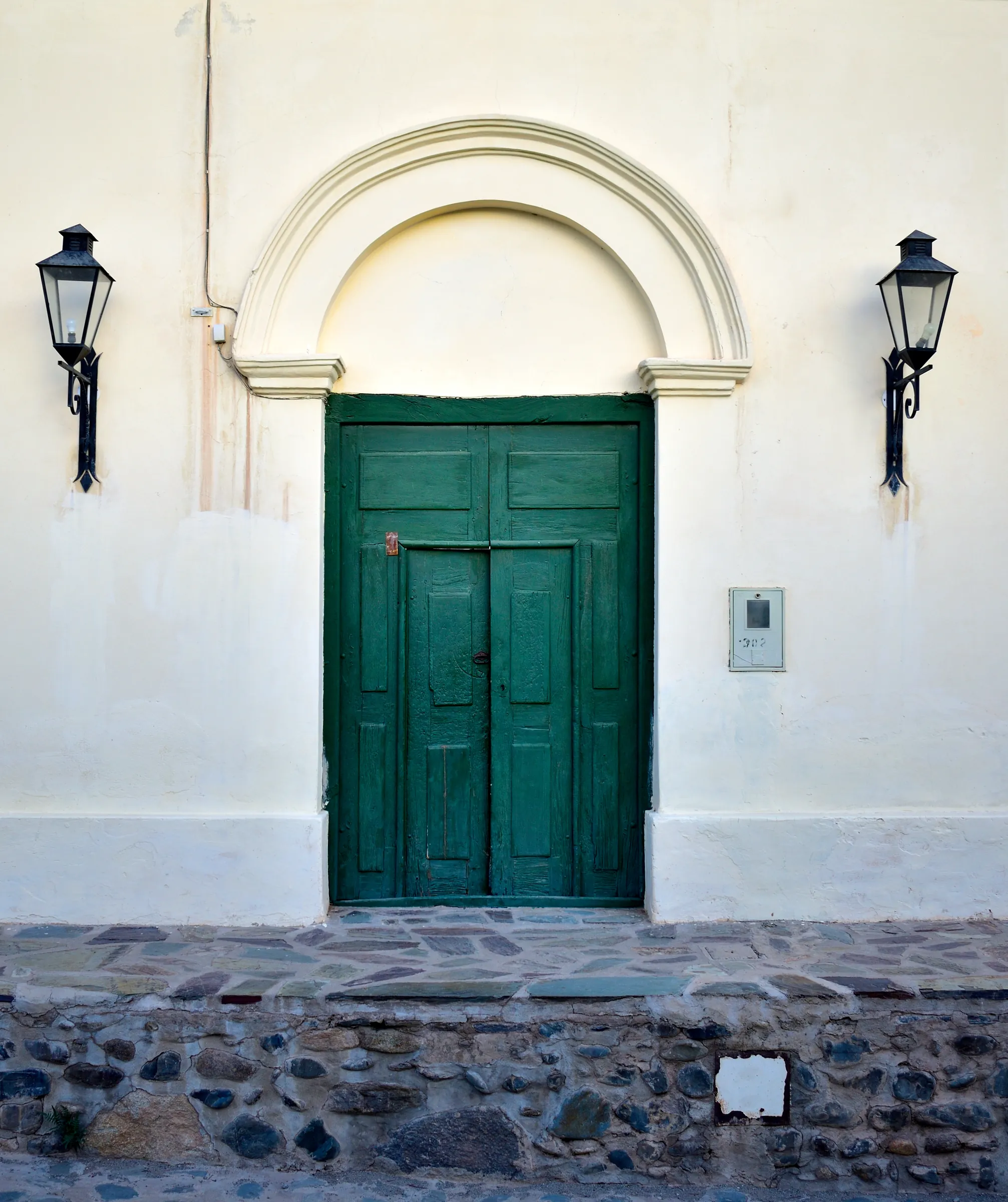 Green door beneath an arched white facade